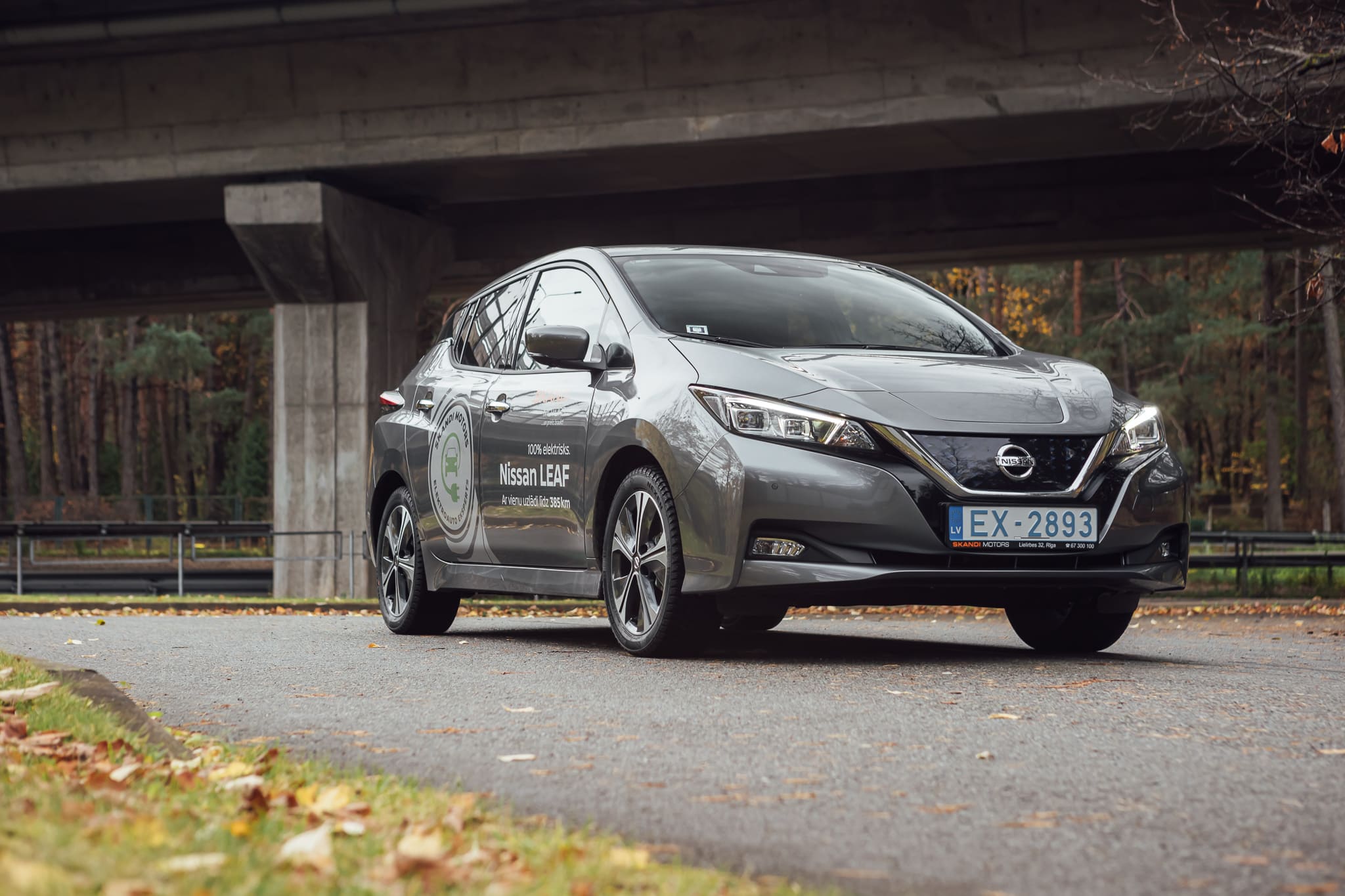 tumši pelēks nissan leaf brauc pa šoseju