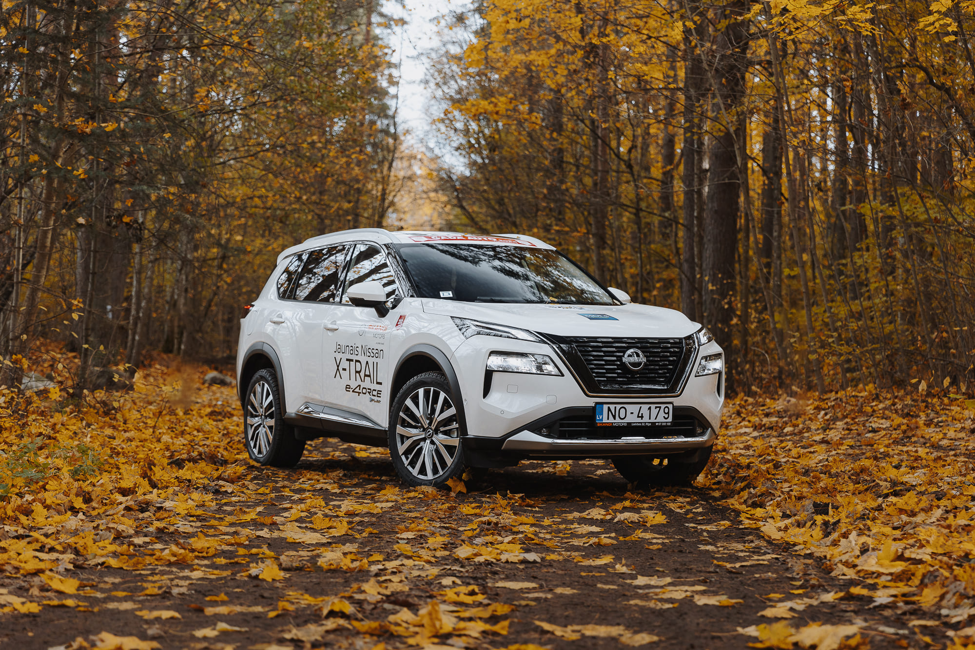 Nissan Xtrail mežā starp rudens lapām
